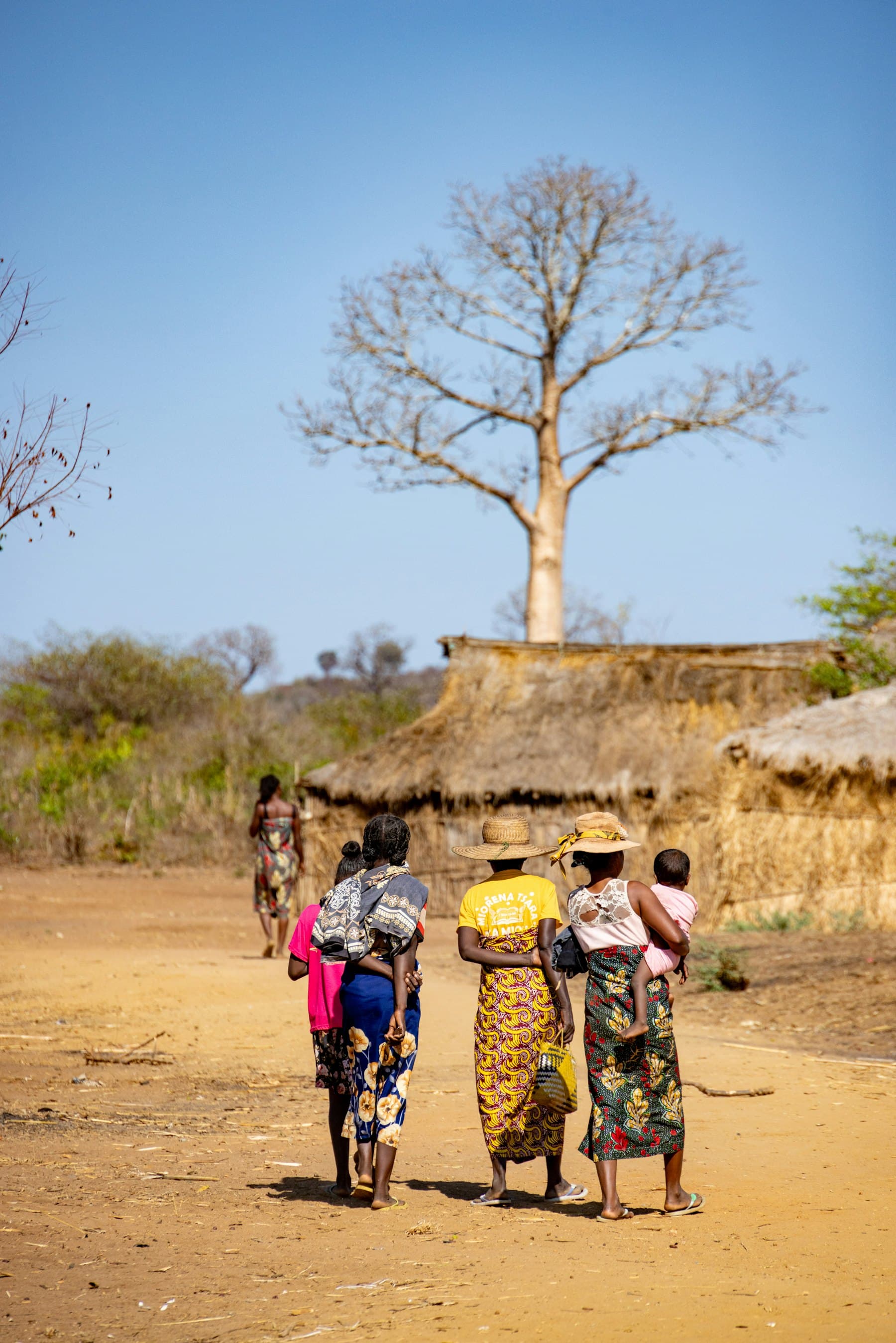 Des femmes portant leurs enfants traversent un village